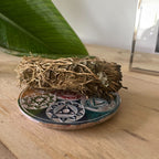 Disque porte-encens 7 chakras en pierre utilisé avec bâton de purification, fumigation, accessoire idéal pour rituel énergétique.