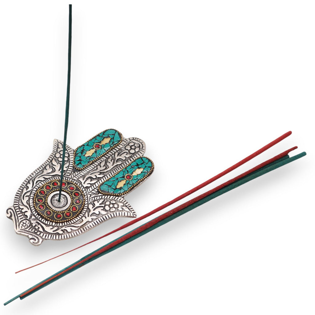 Porte-encens Hamsa vert avec bâton d’encens allumé, utilisé pour rituel de méditation et purification énergétique dans un espace bien-être.