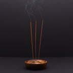 porte encens en bois naturel avec trois bâtons d encens allumés diffusant une fumée apaisante dans une ambiance méditation