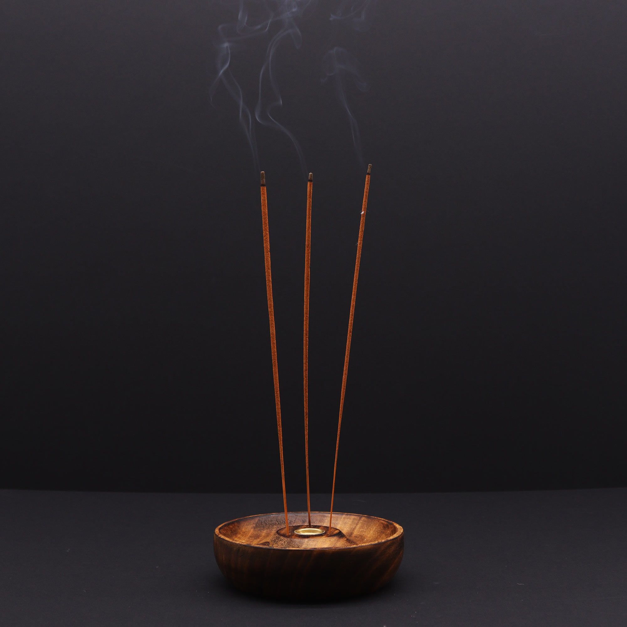 porte encens en bois naturel avec trois bâtons d encens allumés diffusant une fumée apaisante créant une ambiance zen et méditative