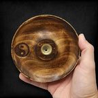 porte encens rond en bois naturel avec symbole yin yang gravé tenu dans la main montrant sa fabrication artisanale