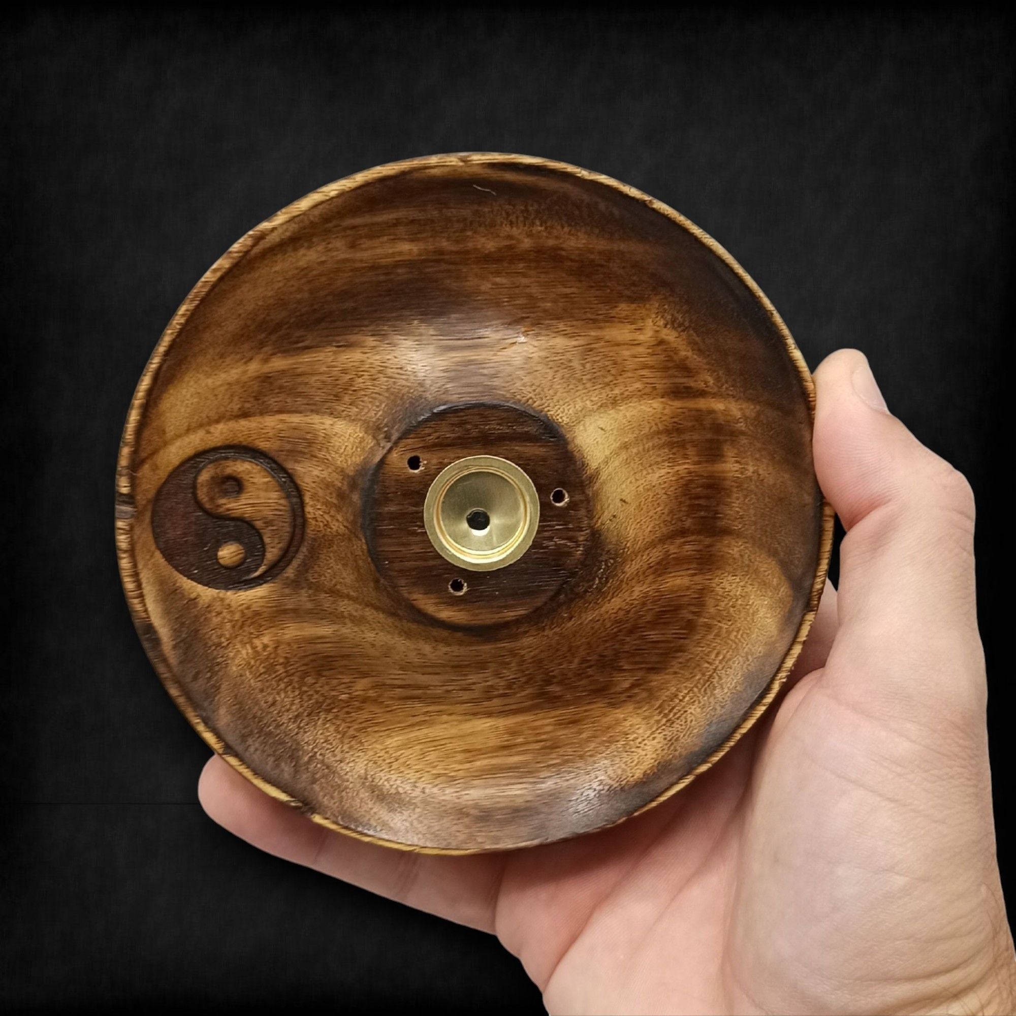 porte encens rond en bois naturel avec symbole yin yang gravé tenu dans la main montrant sa fabrication artisanale