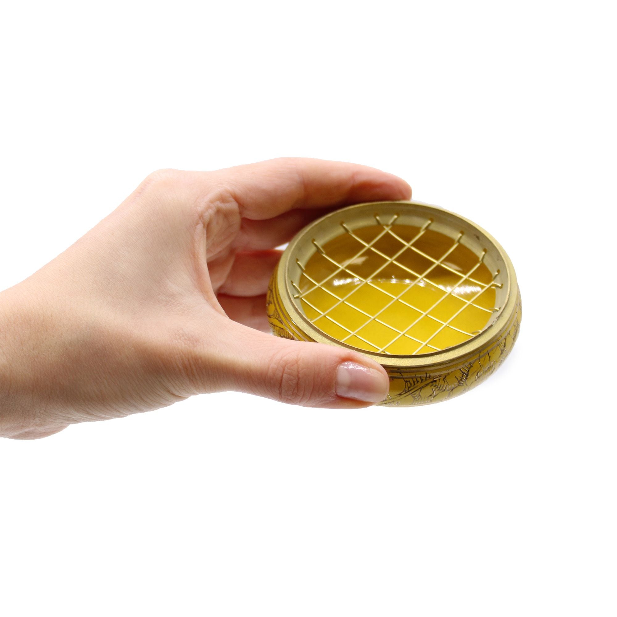Main tenant un brûleur d’encens jaune au charbon en laiton, utilisation lors d’un rituel énergétique chakra plexus solaire
